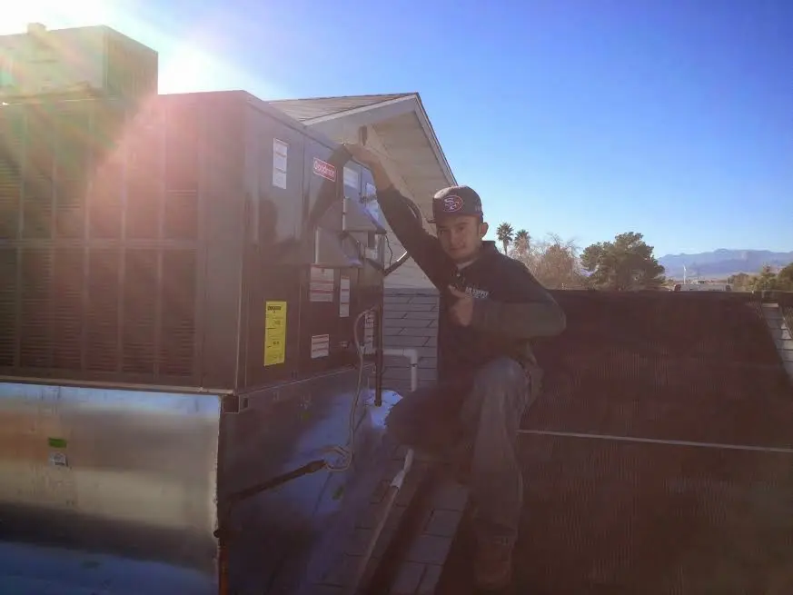 HVAC technician performing Heat Pump Repair on a rooftop unit in Lyon